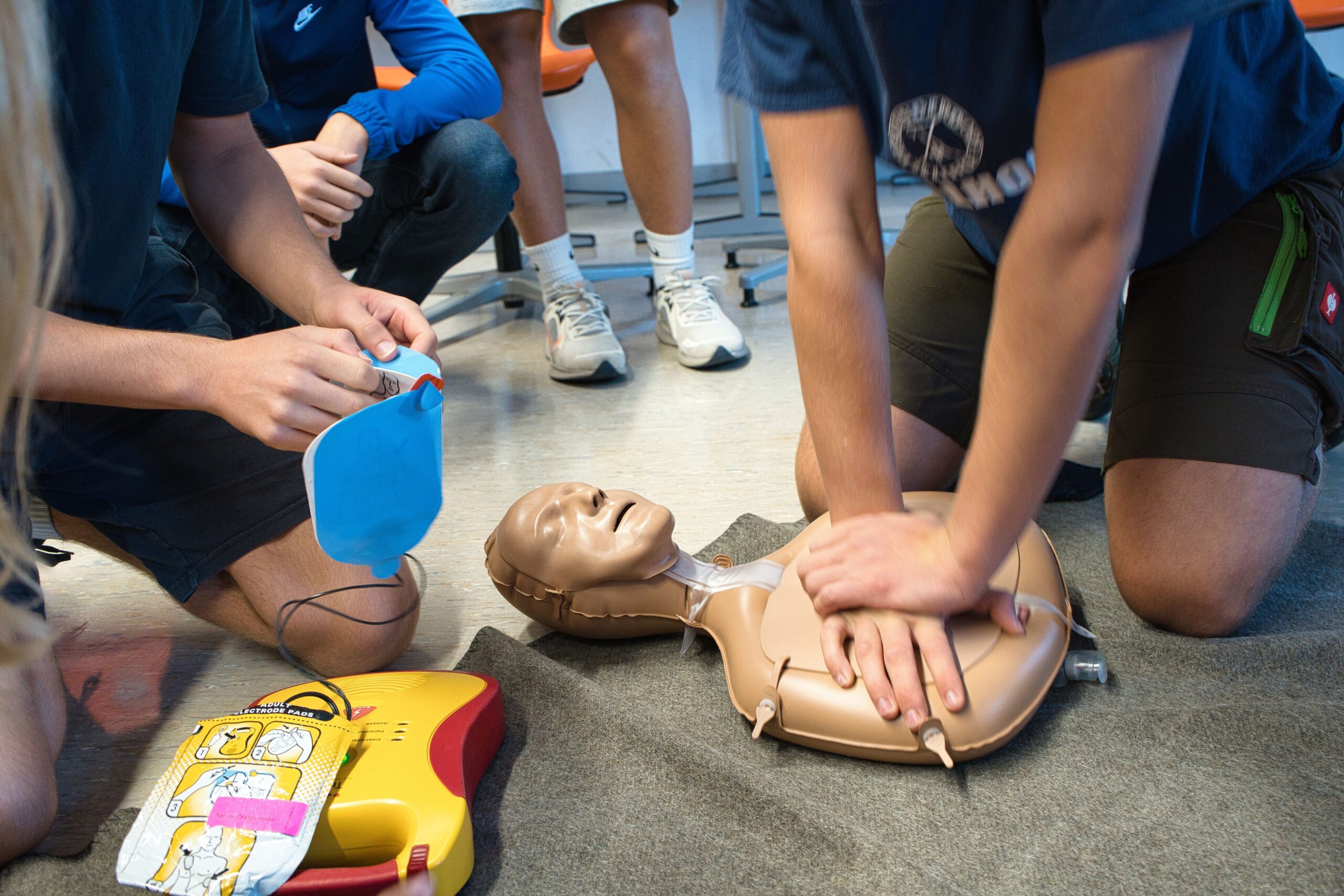 Das Bild zeigt Schülerinnen und Schüler, die an einer Übungspuppe eine Reanimation trainieren.