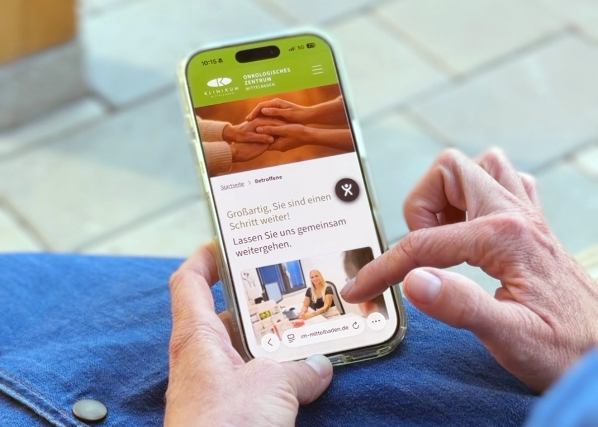 Das Bild zeigt Hände, die an einem Smartphone durch die neue Homepage scrollen.